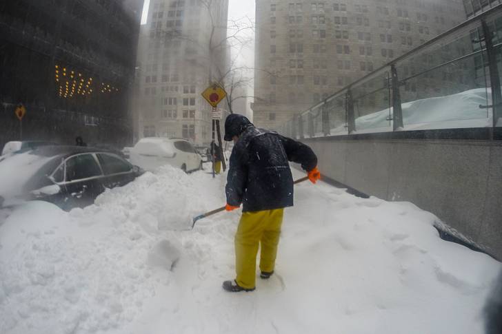 A person shovels snow from a New York City sidewalk following a blizzard.